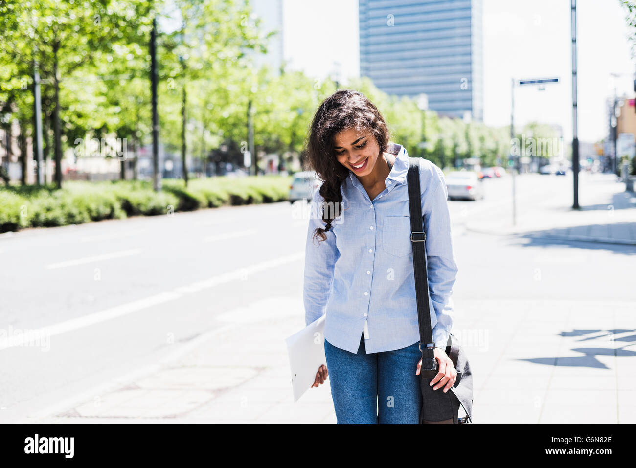 Lächelnde junge Frau in der Stadt unterwegs Stockfoto