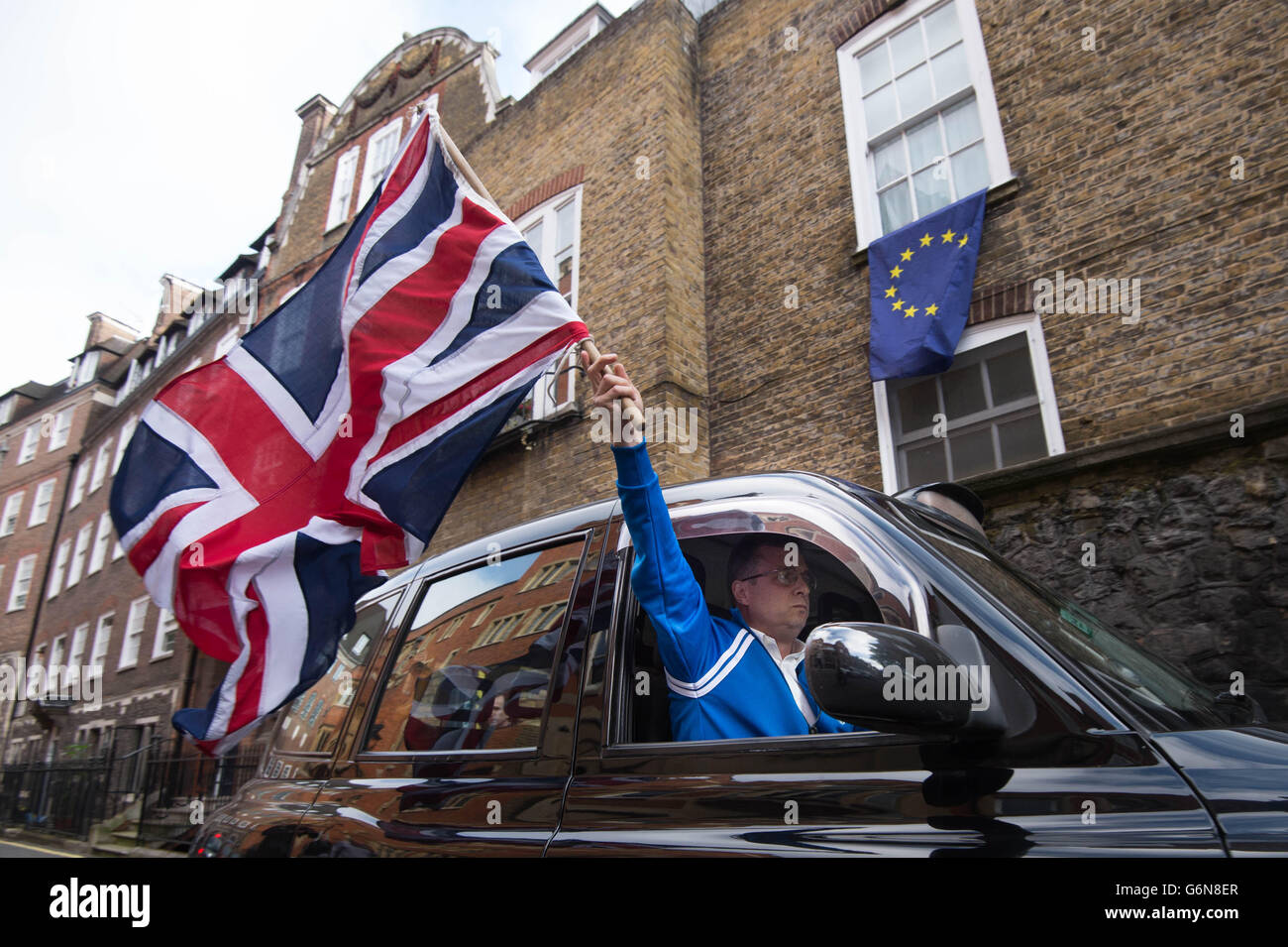 London Taxi-Fahrer winkt ein Union Jack-Flagge in Westminster, London nach Großbritannien gewählt, um die Europäische Union in einer historischen Volksabstimmung verlassen die Westminster Politik in Unordnung geworfen hat und schickte das Pfund auf den Weltmärkten taumeln. Stockfoto