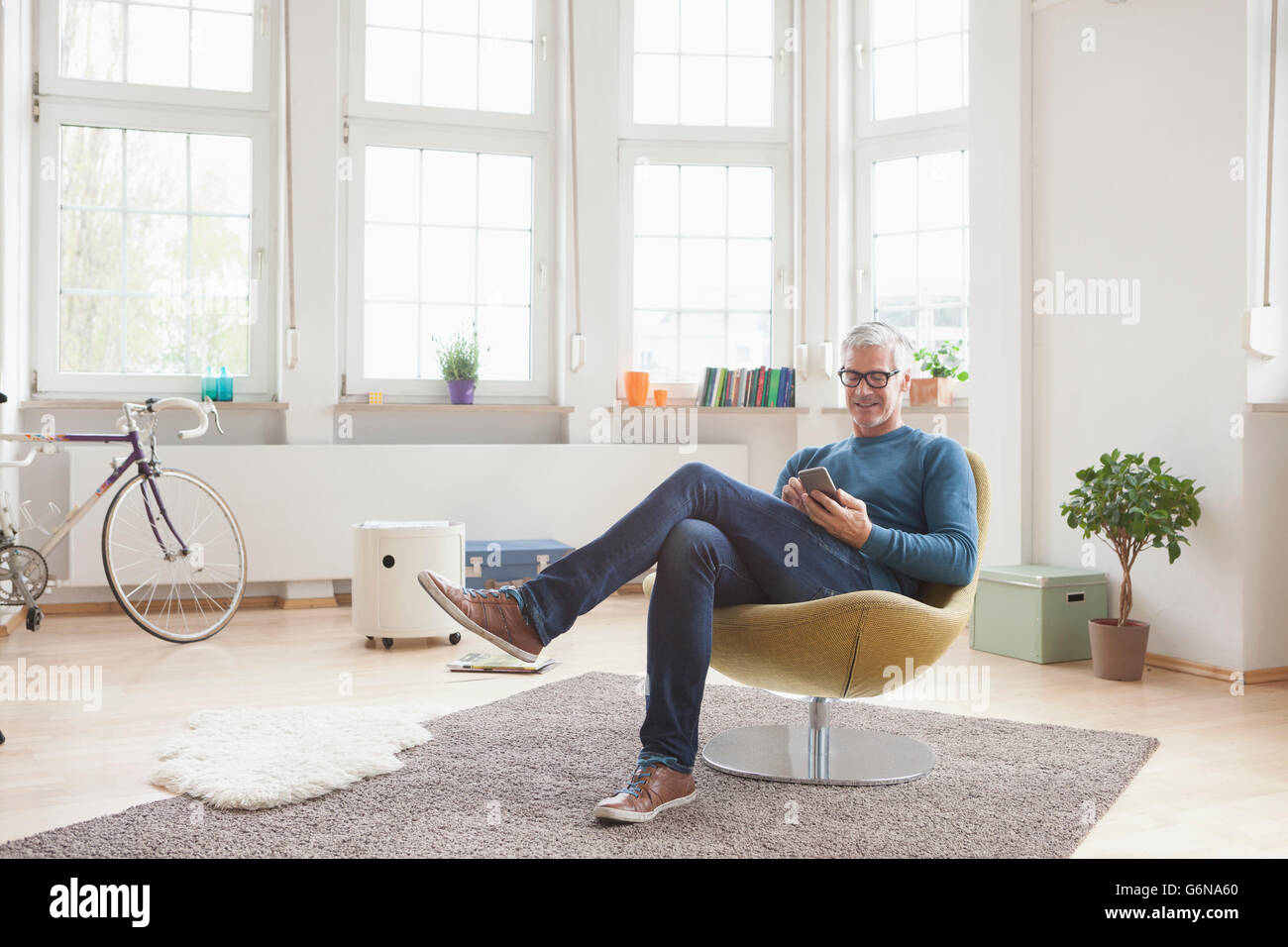 Reifer Mann zu Hause sitzen im Stuhl mit digital-Tablette Stockfoto