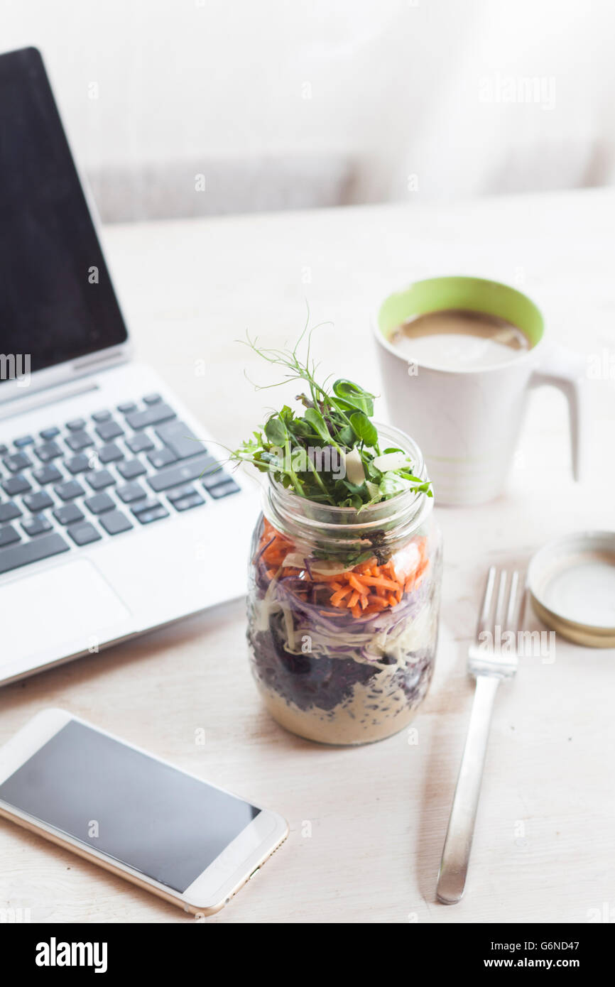 Regenbogen-Salat im Glas, Smartphone, Tasse Kaffee und laptop Stockfoto
