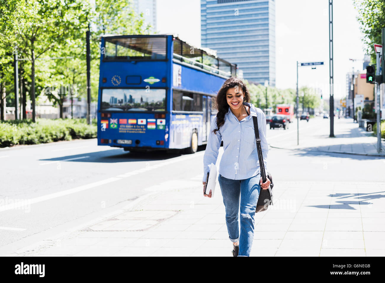 Lächelnde junge Frau in der Stadt unterwegs Stockfoto