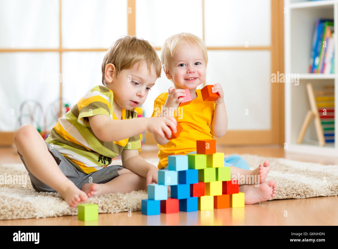 Vorschüler mit bunten Klötzchen spielende Kinder. Kind spielt mit Holz Lernspielzeug im Kindergarten oder Kindertagesstätte. Kleinkind im Kindergarten. Stockfoto