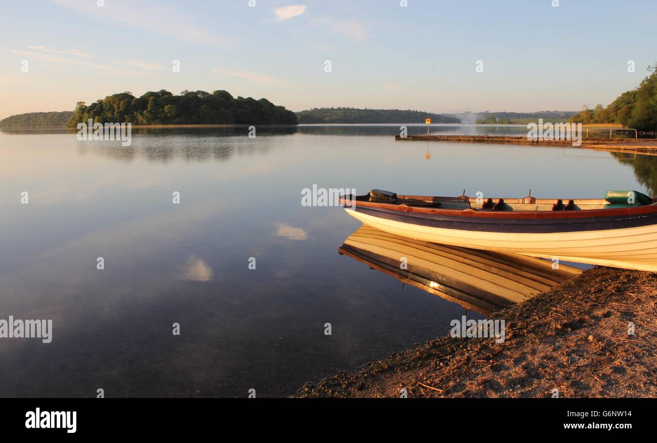 Sonnenaufgang am See, mit Fischerboot im Vordergrund Stockfoto