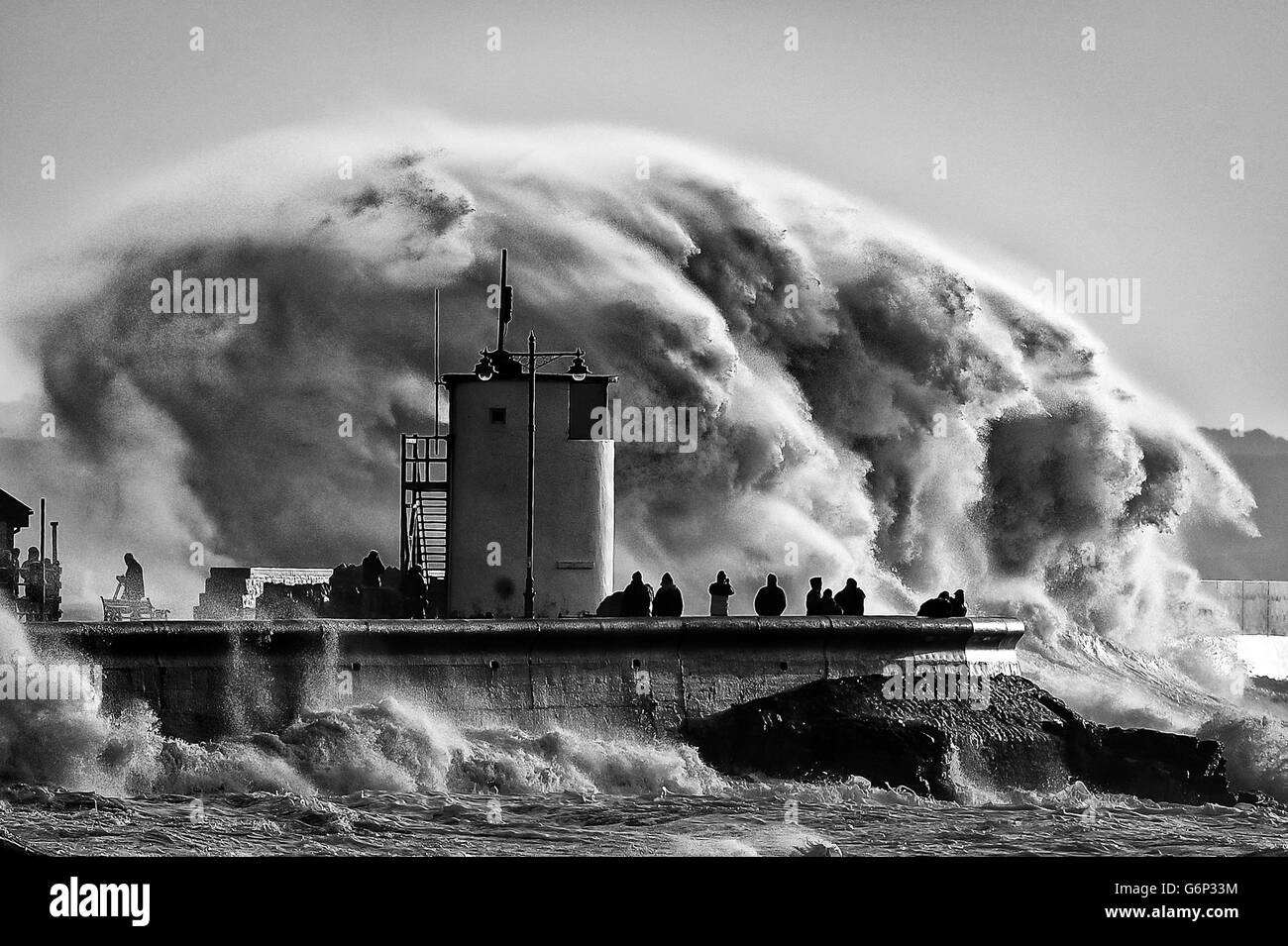 Am Hafen Porthcawl, Südwales, wo sehr starke Winde und hohe See gefährliche Wetterbedingungen erzeugen, beobachten und fotografieren die Menschen riesige Wellen. Stockfoto