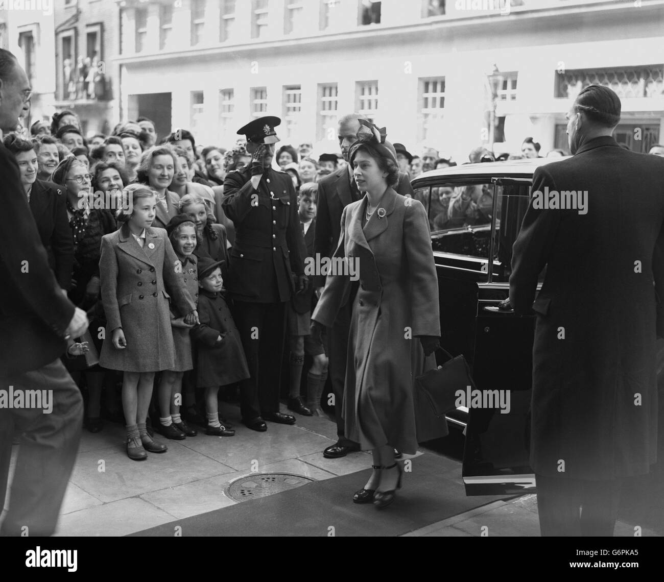 Kinder unter den Zuschauern grüßen Prinzessin Elizabeth und den Herzog von Edinburgh (hinter der Prinzessin), als sie zu einem Besuch im Victory (ex Services) Club in der Seymour Street, London, ankommen. Stockfoto