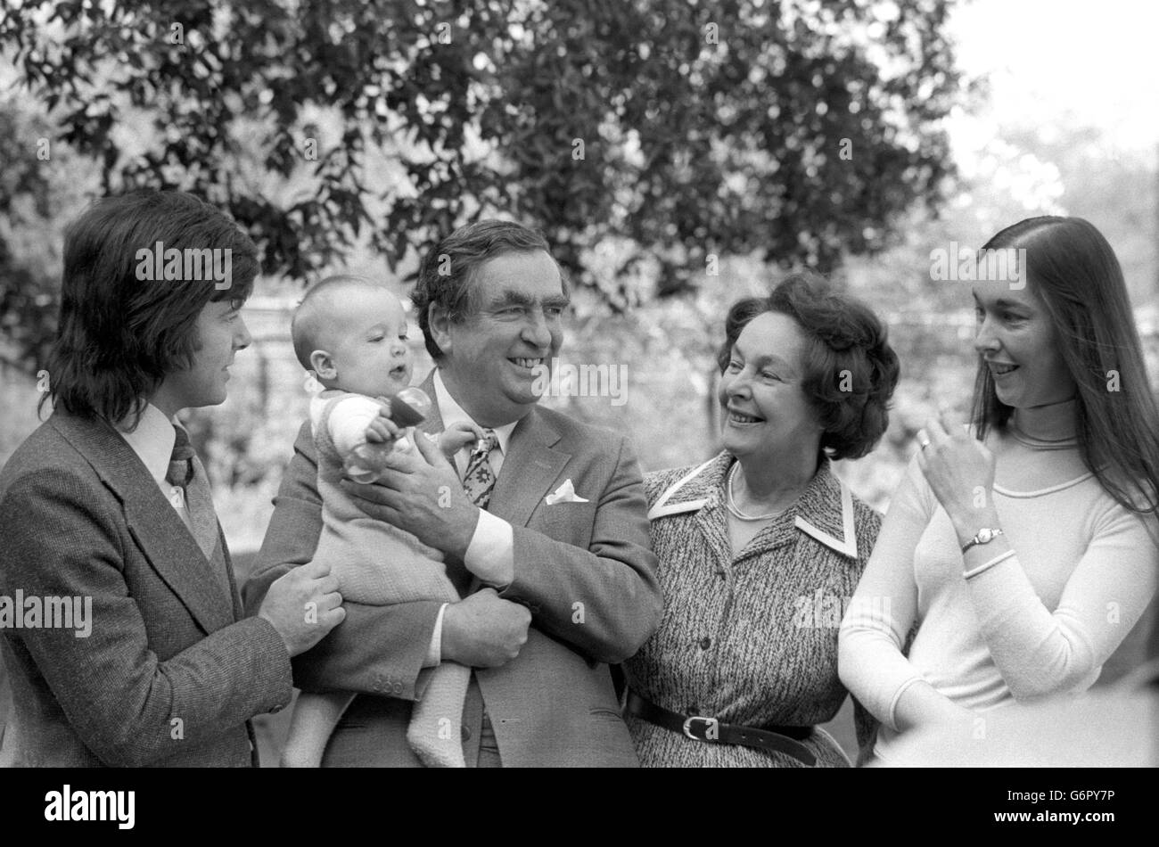 Im Garten der Downing Street Nr. 11 genießt Denis Healey, Schatzkanzler, die Sonne und hält seinen Enkel, den sechs Monate alten Thomas Copsey, fest. Mit ihnen sind die Frau des Kanzlers, Edna, und Thomas's Eltern Jennifer, 27, und Ehemann Derek Copsey, 26. Stockfoto