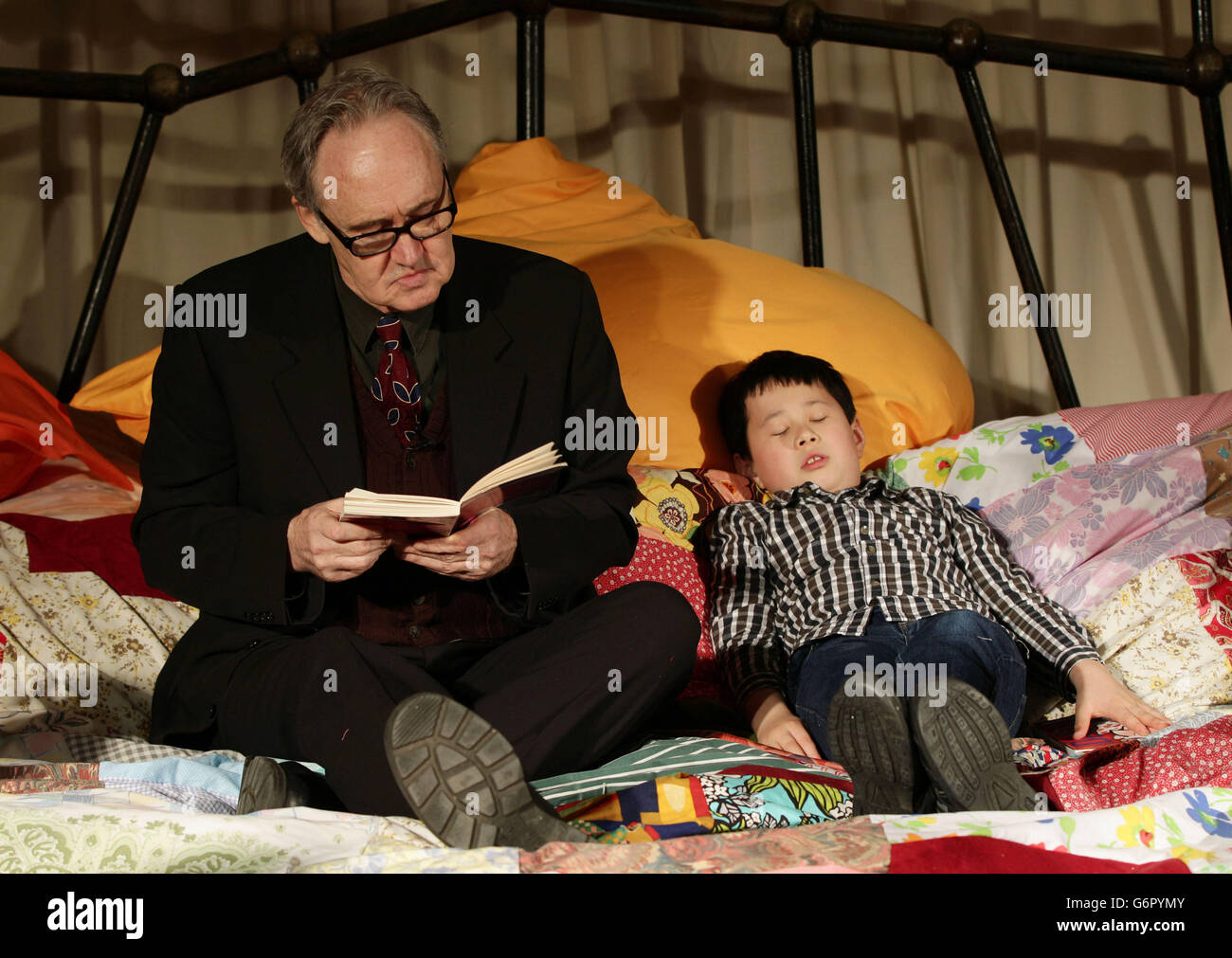 Nigel Planer liest vor einer Gruppe von Kindern - alle von ihnen sind Legastheniker und Studenten mit der Wohltätigkeitsorganisation Dyslexia Action - während der Enthüllung eines 10-mal übergroßen Bettes, das für Massen von Kindern zum Lesen und Vorlesen konzipiert wurde, Während der Eröffnung des Imagine Children's Festival des Southbank Centre in London. Stockfoto