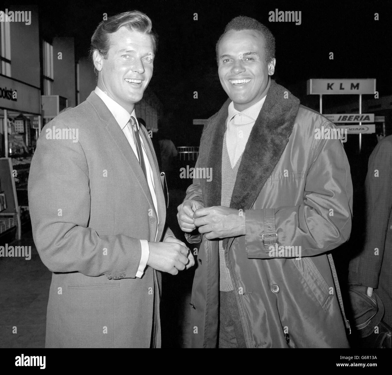 Sänger Harry Belafonte (rechts) von Roger Moore, dem Heiligen der Fernsehserie, gesehen, als er den Flughafen London verließ, um mit einer französischen Gruppe geschäftliche Gespräche zu führen. Roger ist Mitglied eines Komitees, das die Veranstaltung von drei großen europäischen Kundgebungen durch Dr. Martin Luther King, den amerikanischen Bürgerrechtführer, organisieren soll. Stockfoto