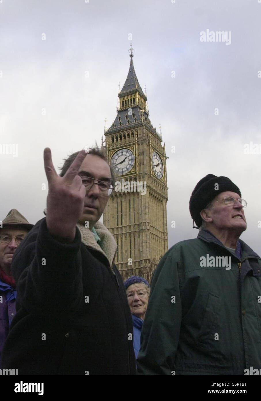 Ein Mann macht ein V-Zeichen, als Demonstranten, die größtenteils aus Rentnern bestehen, gegen steigende Steuererhöhungen im rat demonstrieren, während sie an den Houses of Parliament im Zentrum von London vorbeiziehen. Stockfoto