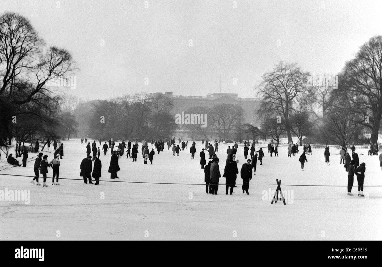 Im Schatten des Buckingham Palace fahren Skater und Slider auf das Eis des gefrorenen St. James's Park Lake, London. Stockfoto