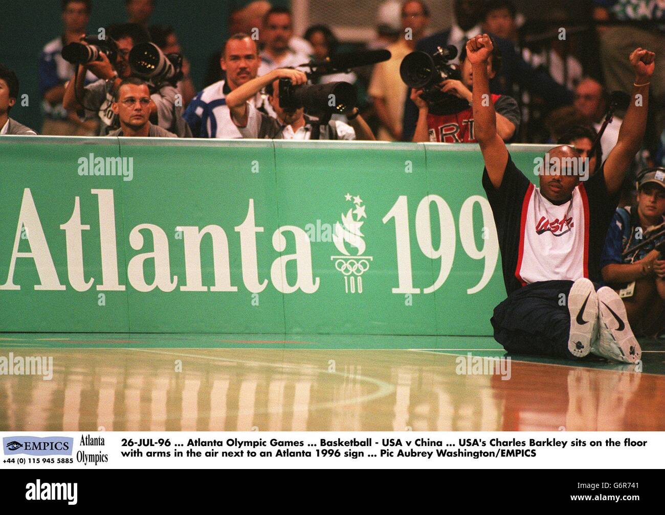 26-JUL-96 ... Atlanta Olympische Spiele ... Basketball - USA / China ... Der US-amerikanische Charles Barkley sitzt auf dem Boden mit Armen in der Luft neben einem Atlanta 1996 Schild Stockfoto