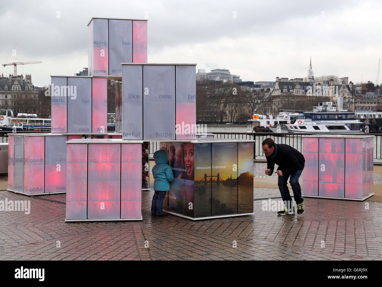 REDAKTIONELLE VERWENDUNG DIE ERST zwei Jahre alte Amy Wood aus Ware in Essex spielt mit ihrem Vater Mike Bagnall in der Londoner Southbank, die von Coca-Cola für ihre Kampagne "Reasons to Believe" in Auftrag gegeben wurde, unter dem Kunstwerk "The Power of Optimismus" des britischen Künstlers David Boultbee. Stockfoto