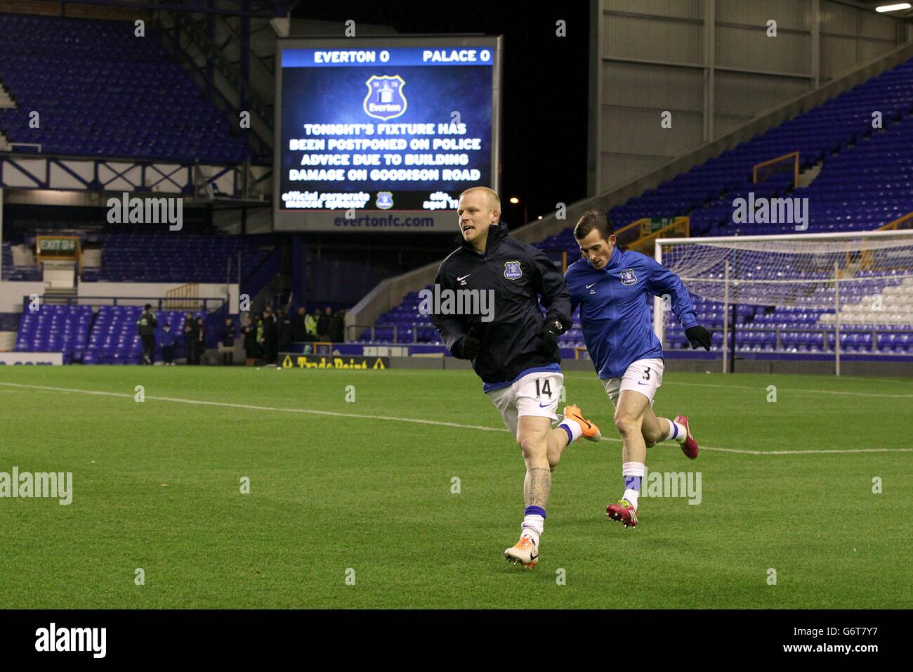 Steven Naismith von Everton und Leighton Baines (rechts) wärmen sich vor dem riesigen Videobildschirm auf und informieren die Fans, dass das Spiel verschoben wurde Stockfoto