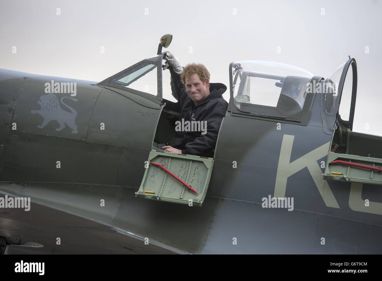 Prinz Harry sitzt in einer Spitfire während eines Besuchs der Boultbee Flight Academy in Goodwood, West Sussex. DRÜCKEN Sie VERBANDSFOTO. Bilddatum: Samstag, 15. Februar 2014. Battle of Britain Veteranen wurden in ihre Zeit als Piloten zurückversetzt, als Harry in das Cockpit der Spitfire kletterte und den Motor während des Starts eines Flugstipendiums für verletzte Ex-Soldaten anfing. Die Kriegsveteranen nahmen an der Teil, um das Spitfire Flight Scholarship zu unterstützen. Das Programm für verwundete ehemalige Militärangehörige und Frauen ist Teil des Endeavour Fund, der von der Royal Foundation of geschaffen wurde Stockfoto