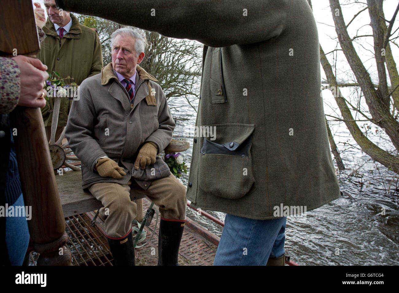 Der Prinz von Wales sitzt auf einer dekorierten Gartenbank auf einem Anhänger, der durch das Hochwasser in Muchelney, Somerset, auf dem Weg zur Thorney Moor Farm fährt. Stockfoto