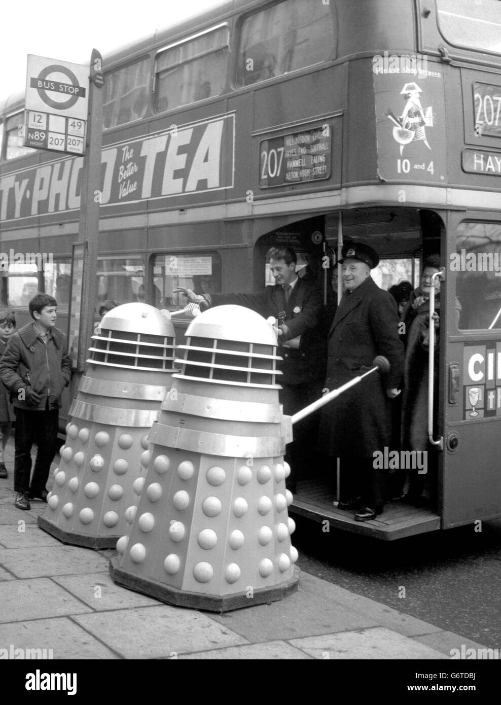 Ein paar Daleks versuchten, einen Londoner Transport Routemaster bei Shepherd's Bush Green zu besteigen, zur Bestürzung des Dirigenten und eines Inspektoren. Stockfoto