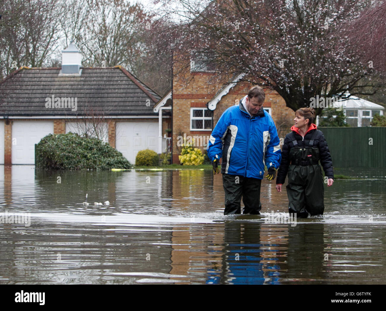 John Matthews und Sally De'Ath Walk machen ihren Weg durch das Hochwasser in Staines-upon-Thames, Surrey. Stockfoto