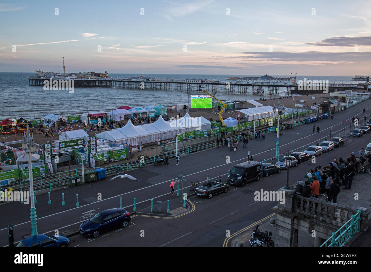 Leute beobachten die Euro 2016-Fußball-Turnier auf einem großen Fernsehbildschirm am Strand in Brighton, England. Stockfoto