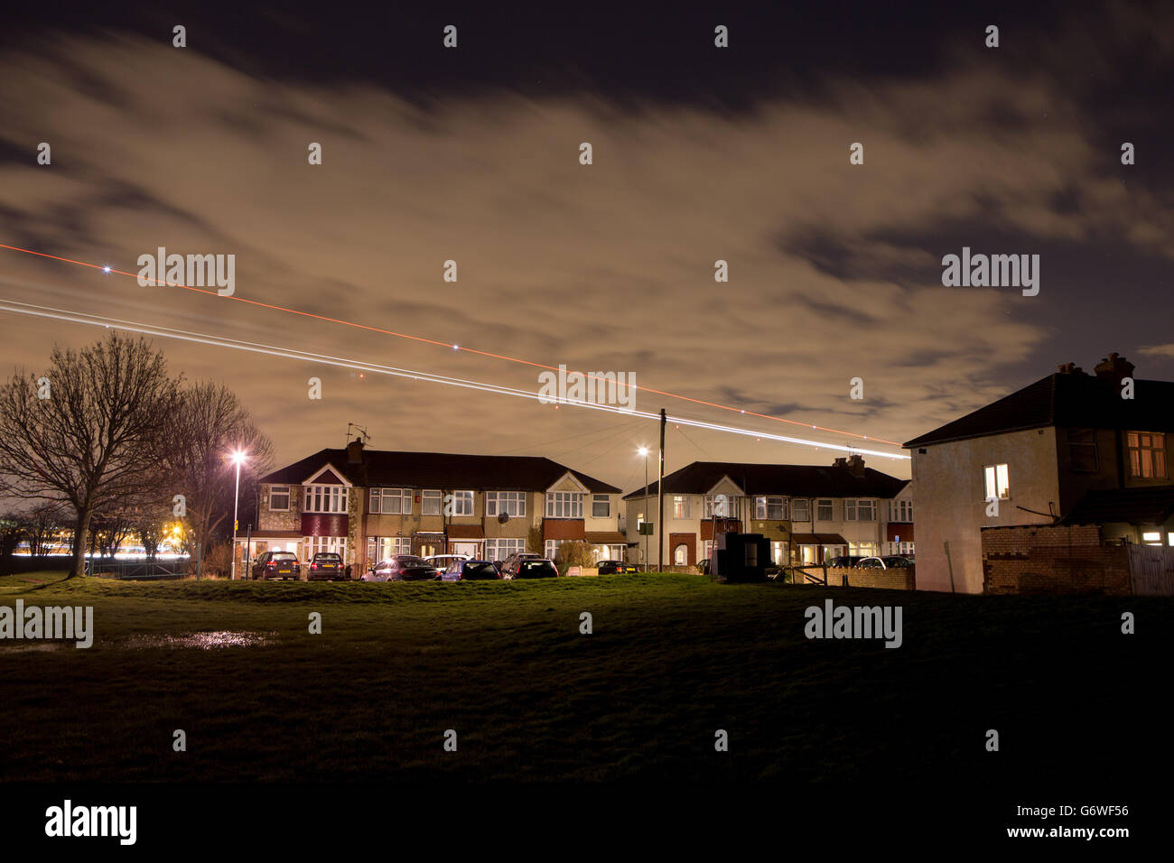 FOTO MIT LANGSAMER VERSCHLUSSZEIT Lichtspuren eines Flugzeugs, das über Häuser im Dorf Bedfont im Großraum London fliegt, während es am Flughafen Heathrow landet. Stockfoto