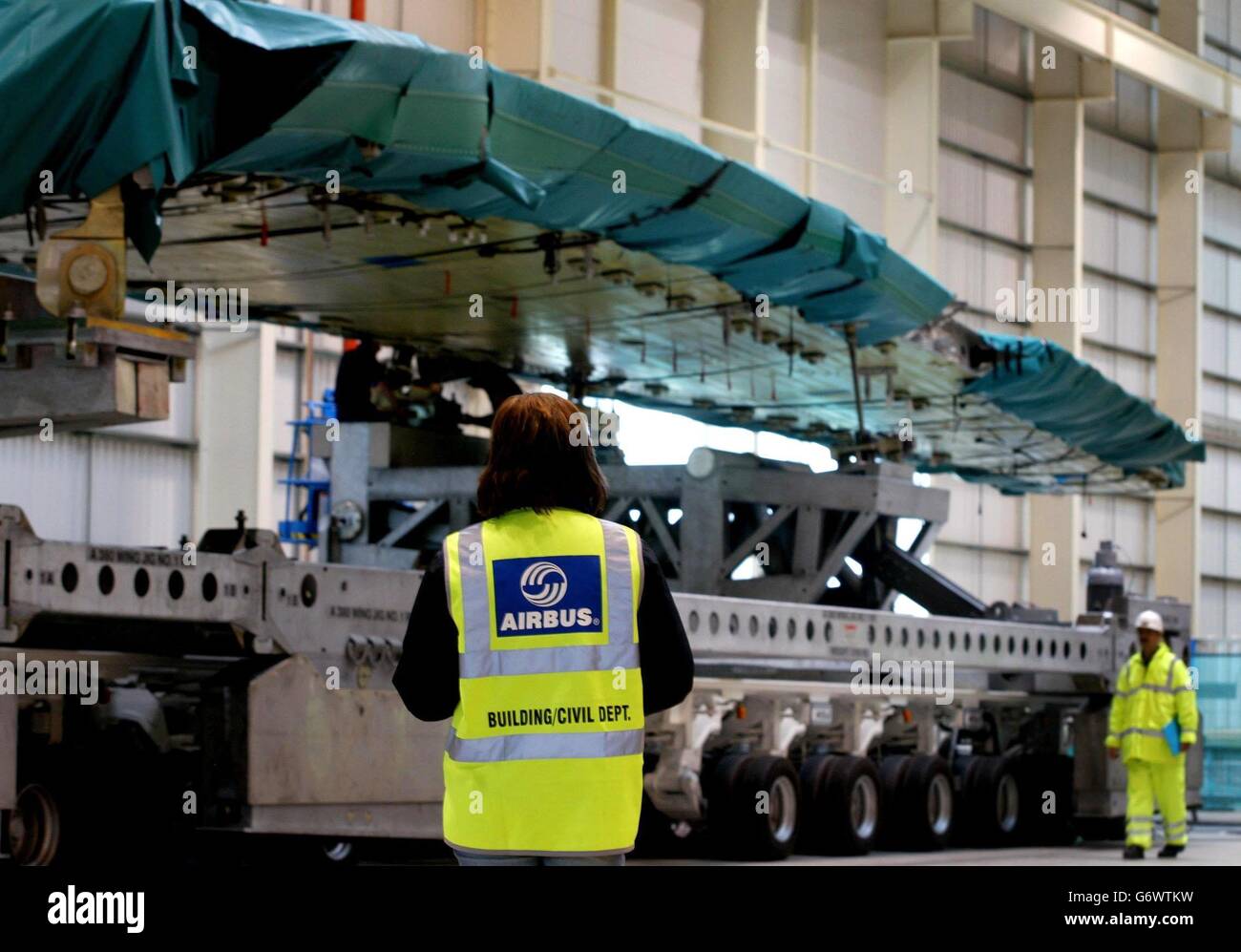 Airbus-Mitarbeiter untersuchen den größten zivilen Flugzeugflügel der Welt, bevor er vom Airbus-Werk in Broughton in der Nähe von Chester zu einem Hafenbecken am Flussufer kommt. Der Flügel, der 38 Tonnen wiegt, misst über 45 Meter, hat seinen massiven Transportbetrieb aufgenommen, der bis zu 4 Wochen dauern wird, zu Land, Fluss und See, der Flügel wird nach Toulouse in Frankreich für die Endmontage für den neuen Doppeldeck airbus A380 verschifft. Stockfoto