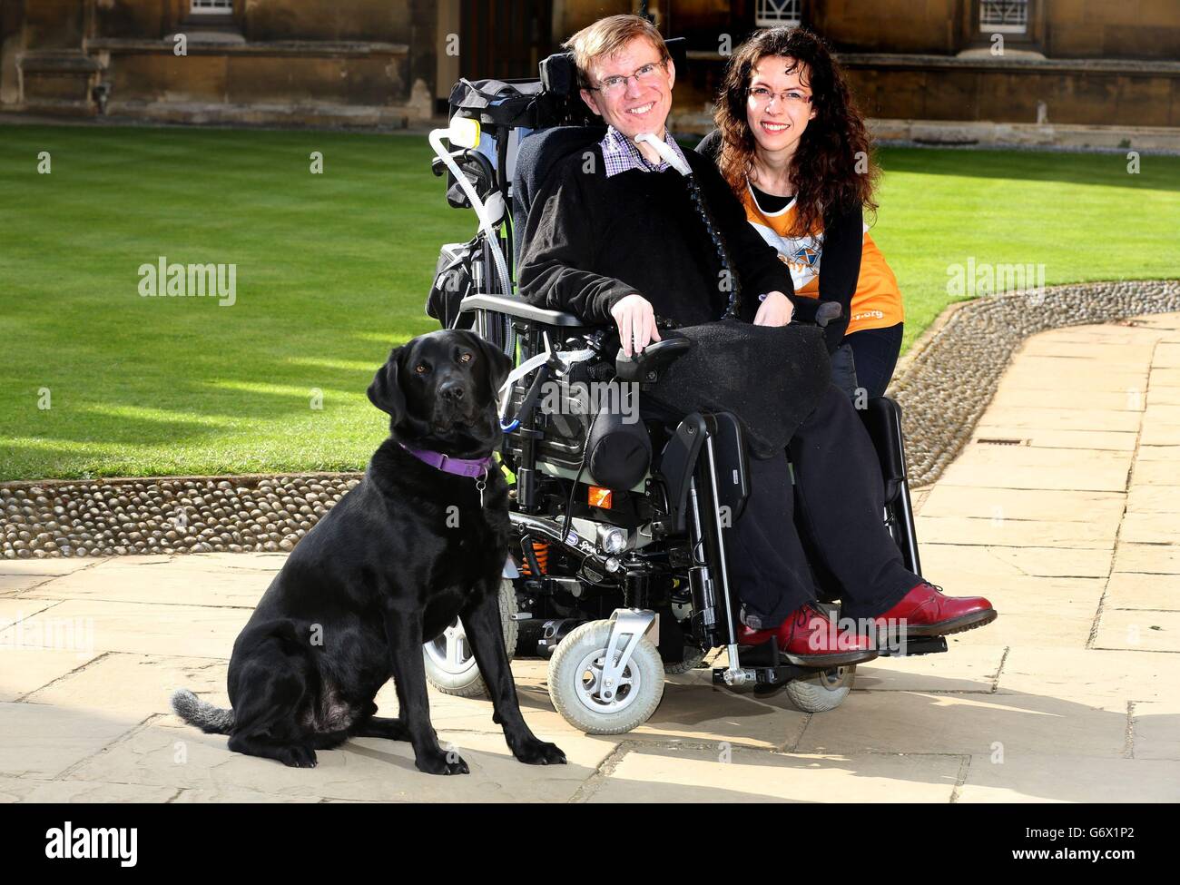 Der Doktorand Jonathan Gilmour, der mit seinem Assistenzhund Uri an einer Duchenne-Muskeldystrophie erklagt, und der auf dem Hof des St. John's College der University of Cambridge die Raiserin Albertyna Paciorek finanziert. Stockfoto