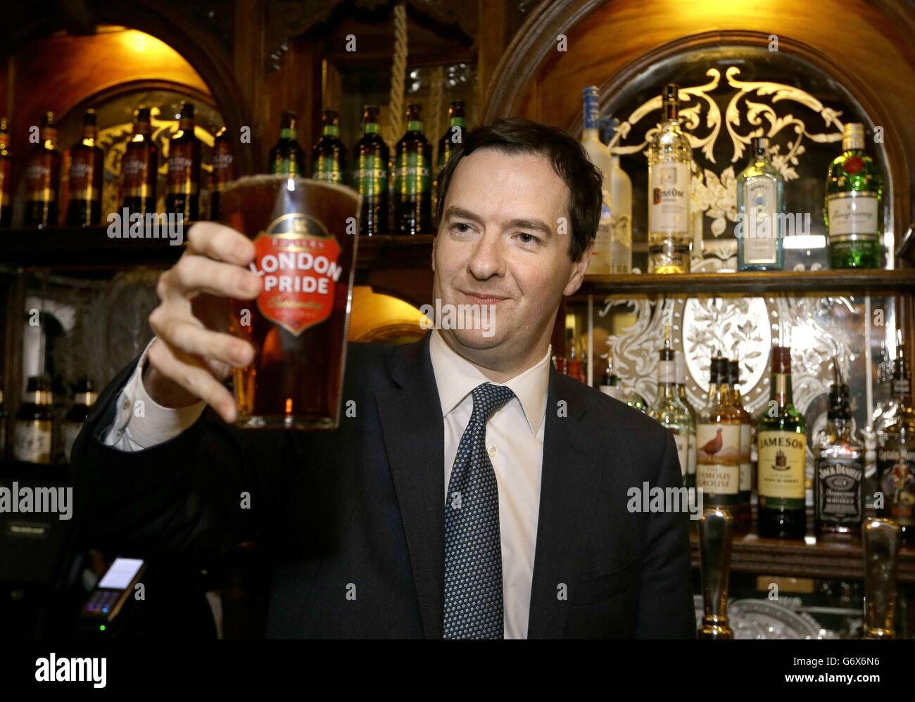 Der Schatzkanzler George Osborne hält ein Pint Bier während eines Besuchs, um den Red Lion Pub nach einer großen Renovierung in Whitehall, im Zentrum von London, offiziell wieder zu eröffnen. Stockfoto