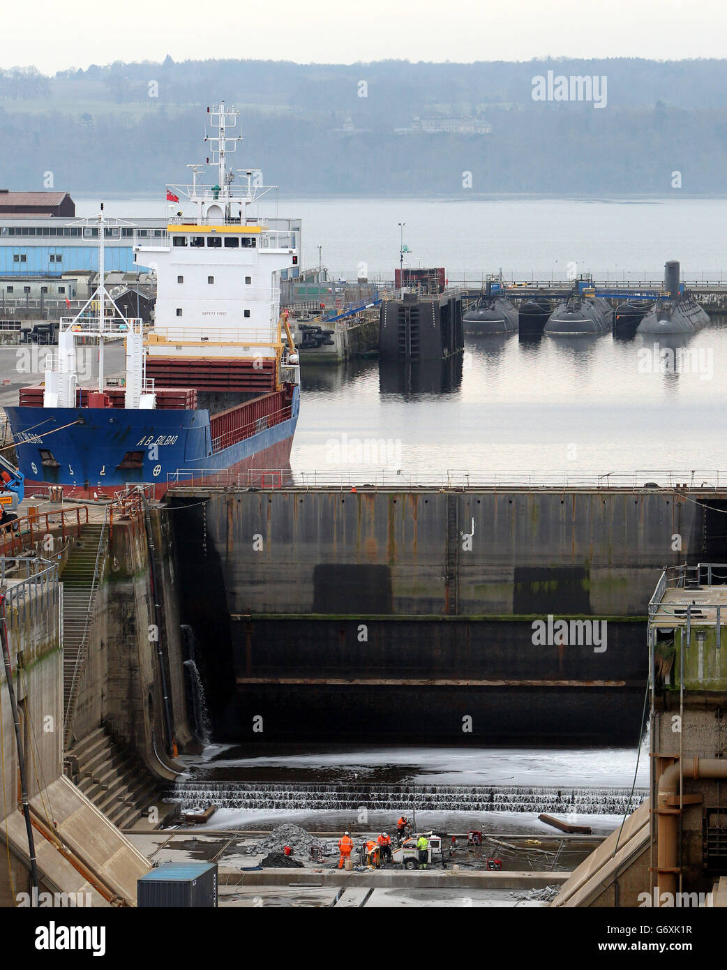 Arbeiter führen Wartungsarbeiten an einem nahe gelegenen Trockendock durch, während die Arbeiten an HMS Queen Elizabeth Aircraft Carrier in einem nahe gelegenen Dock an den Rosyth Docks in Fife fortgesetzt werden. Stockfoto