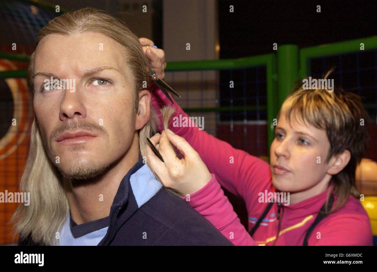 Das Wachsmodell von David Beckham lässt sich bei Madame Tussauds im Zentrum von London die Haare schneiden, während sich der hauseigene Haar- und Farbkünstler Alison Tisson darauf vorbereitet, das Erscheinungsbild des Modells nach Beckhams neuestem Friseurwechsel zu verändern. Stockfoto