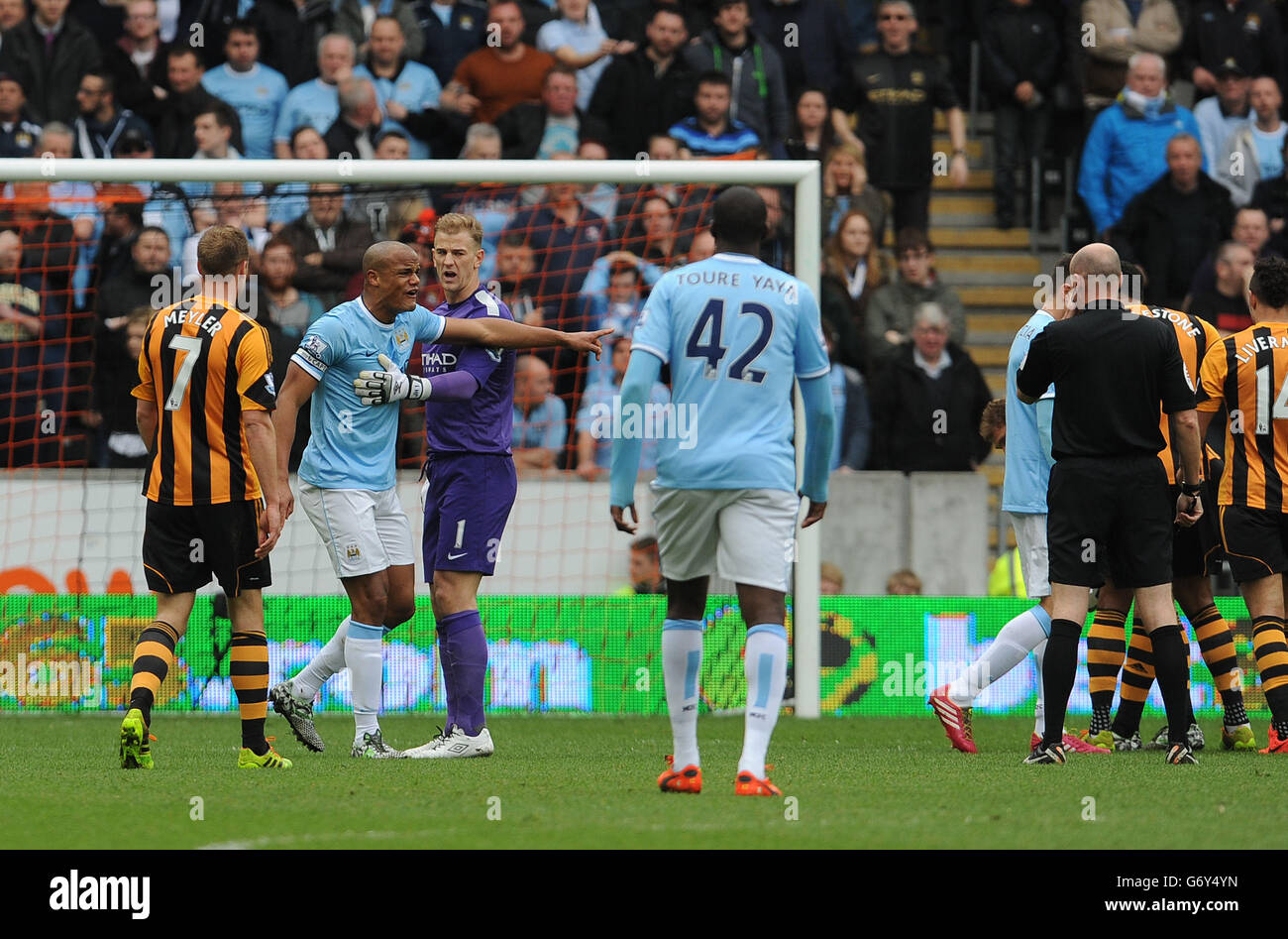 Vincent Kompany von Manchester City wird von Joe Hart zurückgehalten, als er mit Schiedsrichter Lee Mason argumentiert, nachdem er während des Spiels der Barclays Premier League im KC Stadium, Hull, abgeschickt wurde. Stockfoto