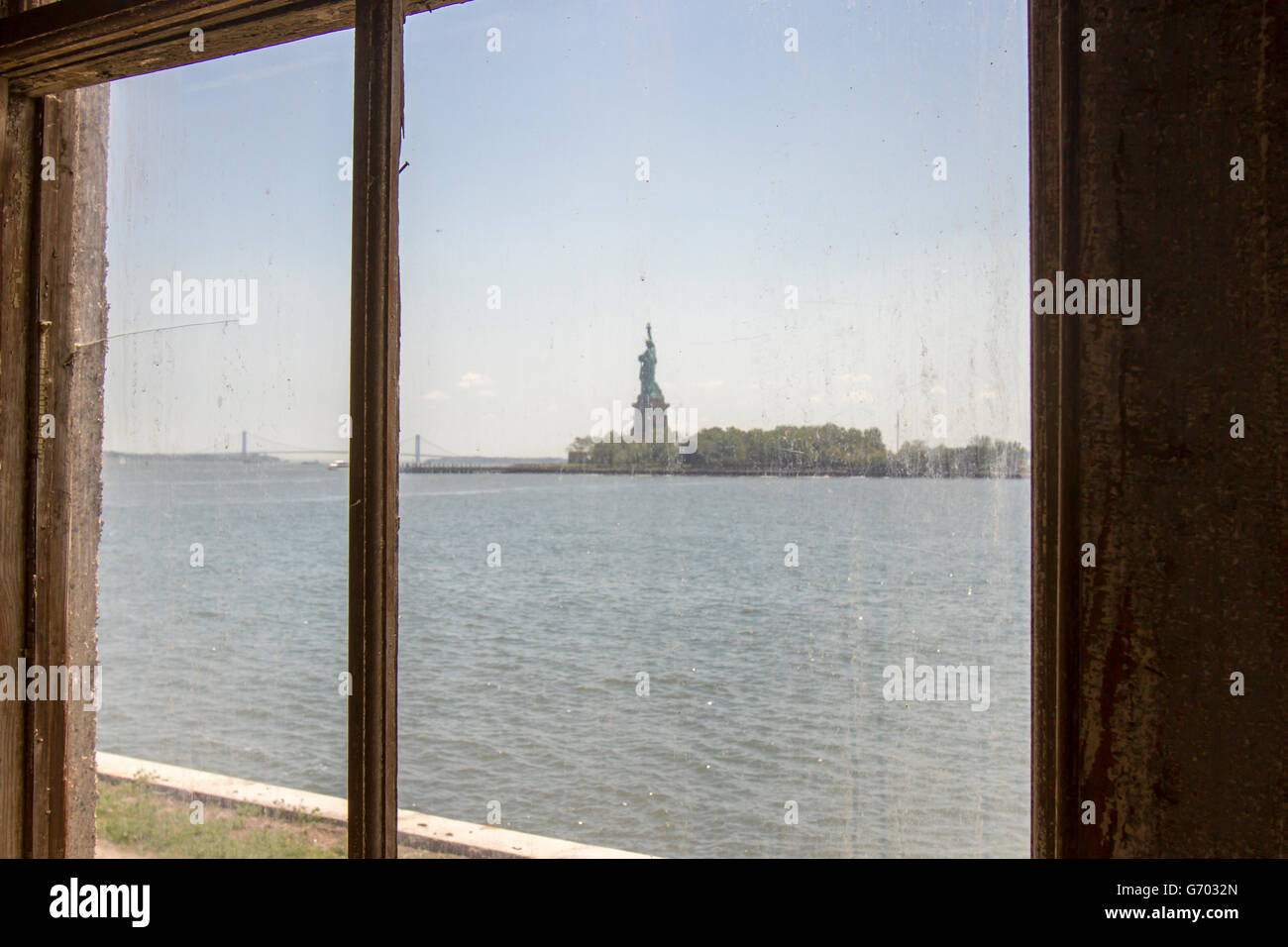Anzeigen des Status von Liberty durch schmutzige Fenster der verlassenen Klinikgebäude auf Ellis Island. Stockfoto