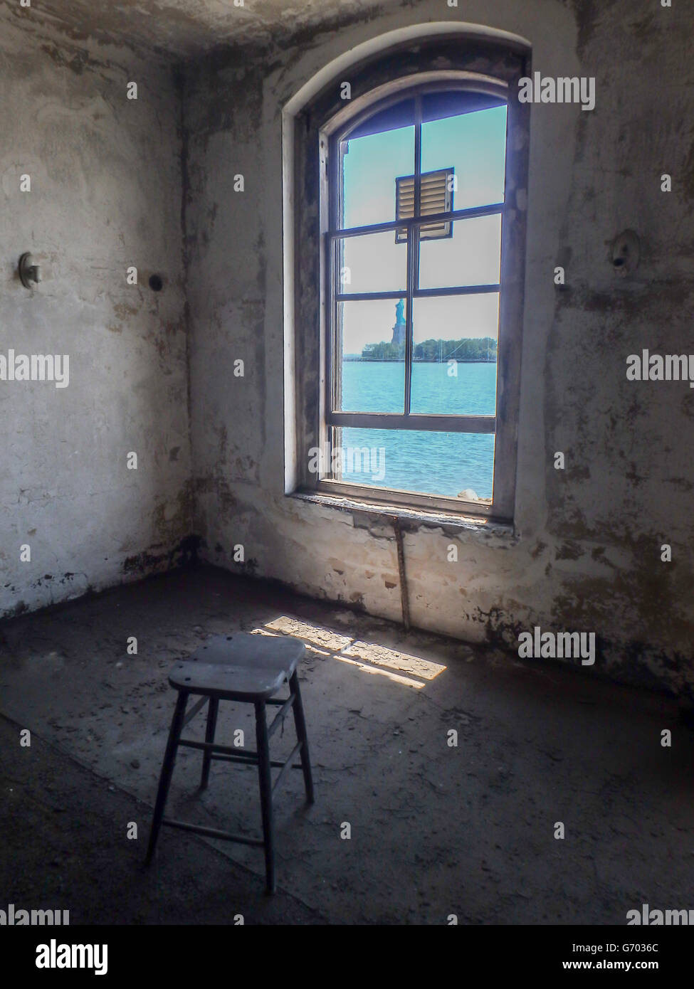 Blick auf die Freiheitsstatue aus dem Fenster des verlassenen Ellis Island Krankenzimmer mit Hocker. Stockfoto