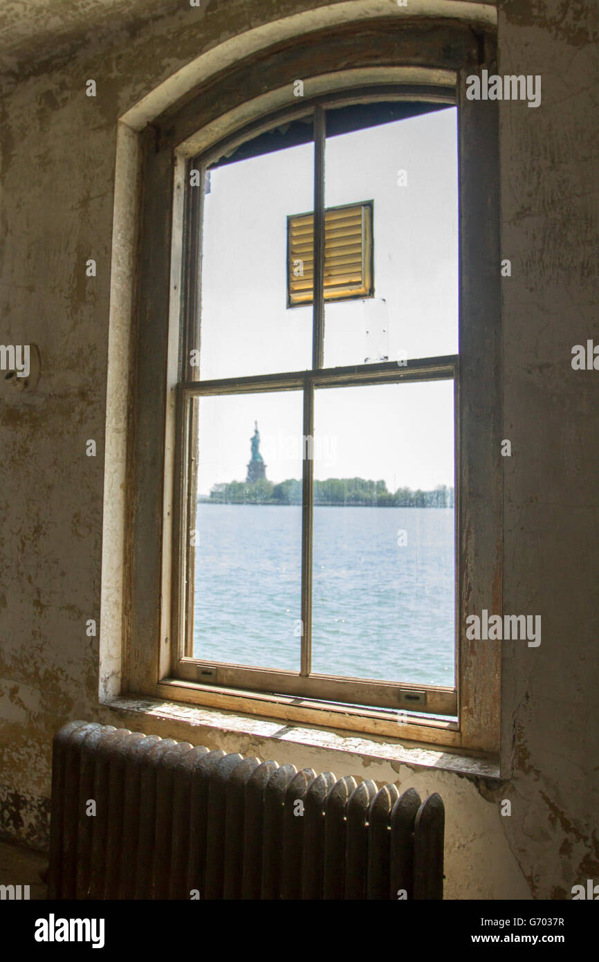 Freiheitsstatue durch schmutzige Fenster der verlassenen Gebäude des Krankenhauses Ellis Island. Stockfoto