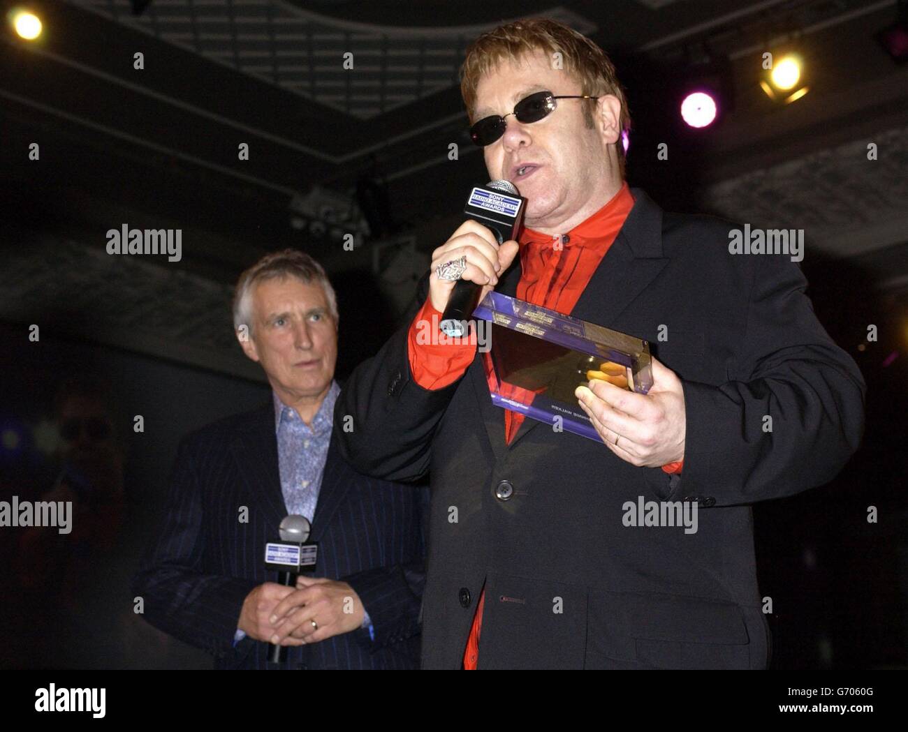 Sir Elton John (rechts) überreicht den Gold Award an Radio 2 DJ Johnnie Walker, der während der Sony Radio Academy Awards 2004 im Grosvenor House Hotel in der Park Lane, London, auf der Bühne steht. Bei der Zeremonie verloren Jonathan Ross und Chris Moyles von Radio 1 gegen Christian O'Connell von XFM, der zum DJ des Jahres ernannt wurde. Stockfoto