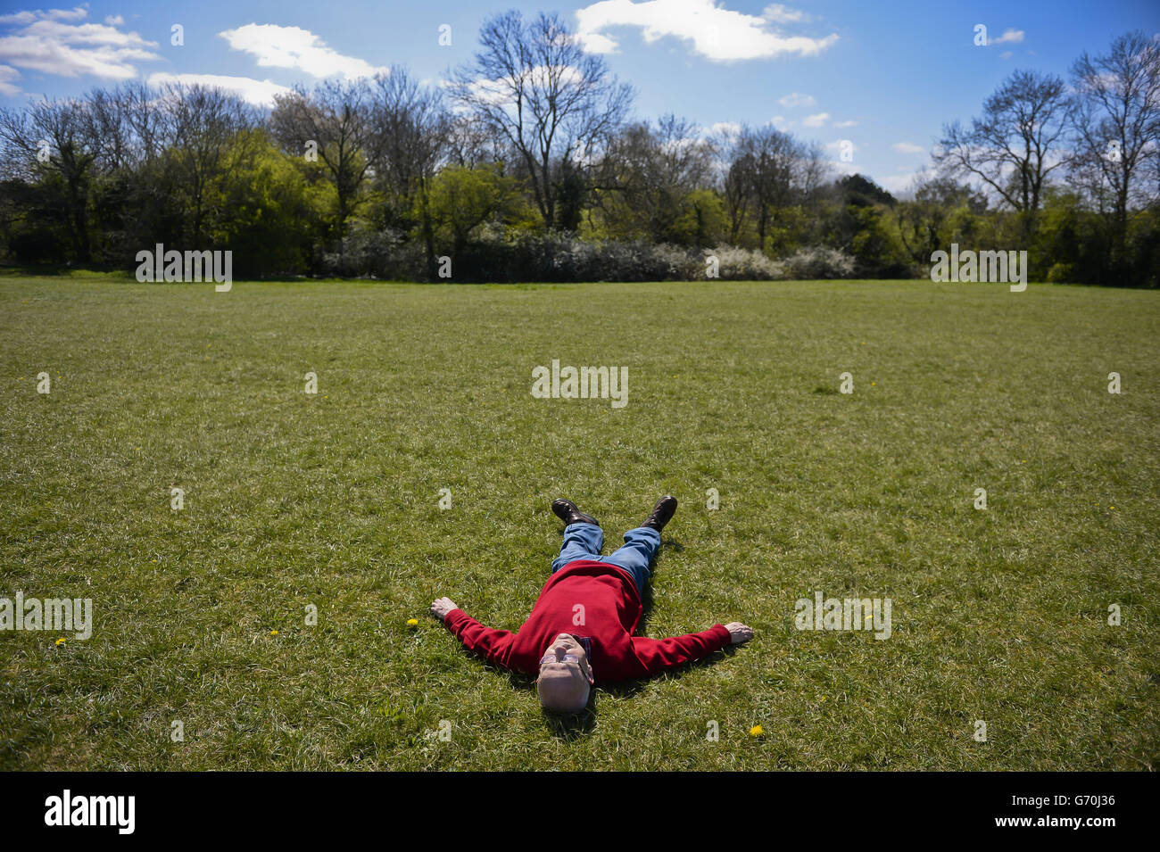 Ein Mann entspannt sich in der Sonne auf dem Gras in Clifton Downs, Bristol. Stockfoto