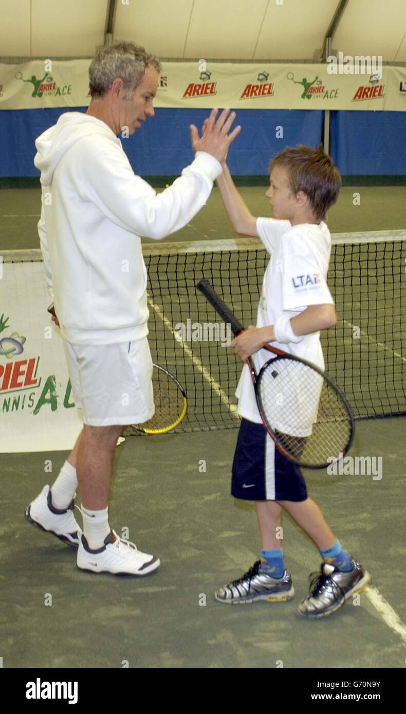 Tennis-Legende John McEnroe dient ein Champion und hilft Ariel Tennis Ace Jack Dixon, von Scunthorpe, machen Sie sich bereit, die große Berühmtheit Wimbledon Finale am 14. Juni, in Lawn Tennis Association Academy. Stockfoto