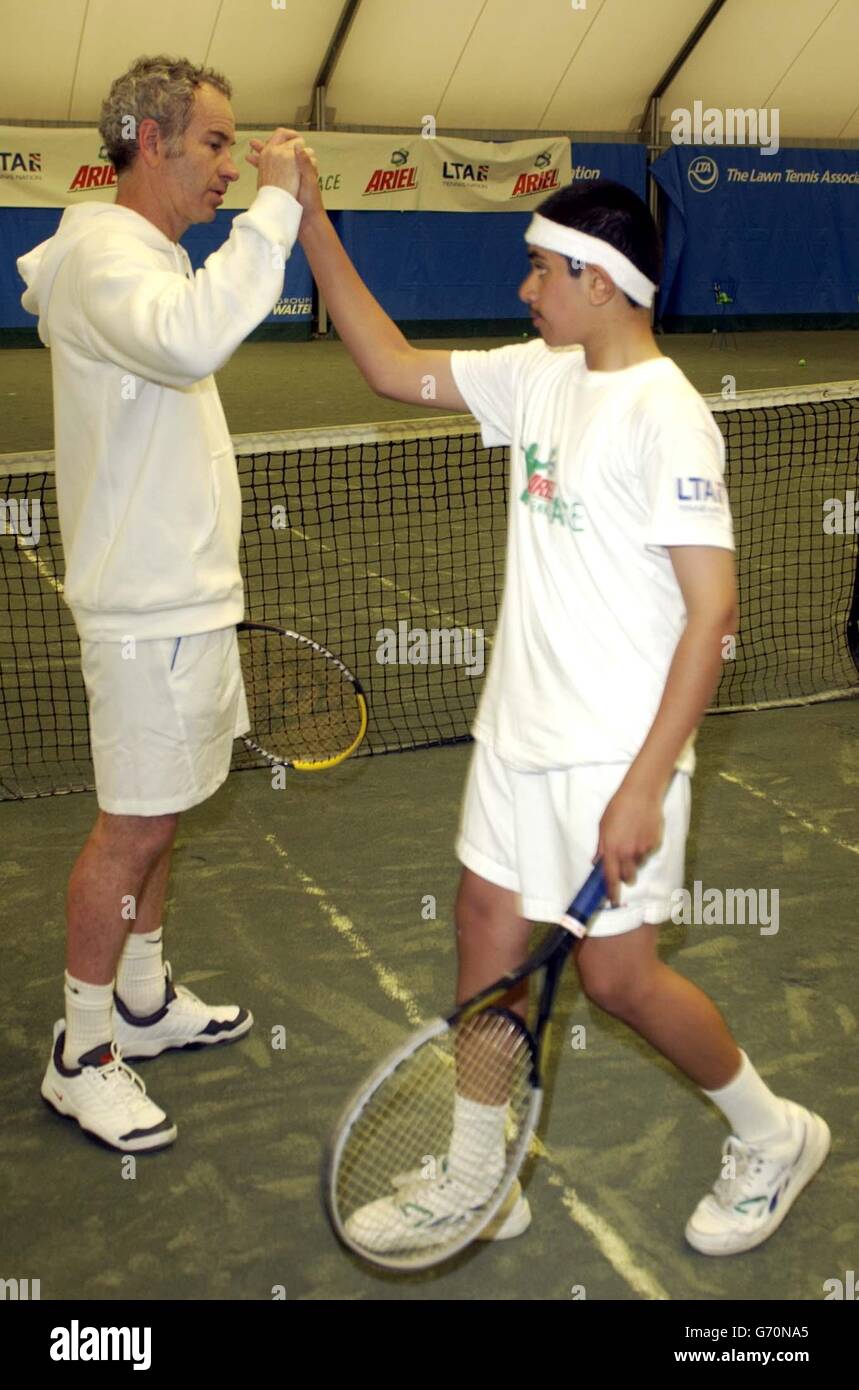 Tennis-Legende John McEnroe dient ein Champion und hilft Ariel Tennis Ace Shaakir Salam, von Tyne-in-Wear, machen Sie sich bereit, die große Berühmtheit Wimbledon Finale am 14. Juni, in Lawn Tennis Association Academy. Stockfoto