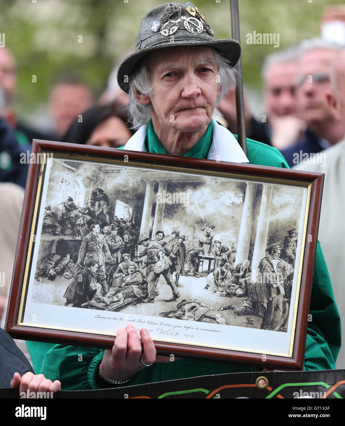 EIGENSTÄNDIGES Foto. Ein Mann trägt ein Gemälde, das eine Szene aus dem Osteraufstand von 1916 während der Sinn Fein-Gedenkfeier anlässlich des 98. Jahrestages des Osteraufstands von 1916 in Dublin darstellt. Stockfoto