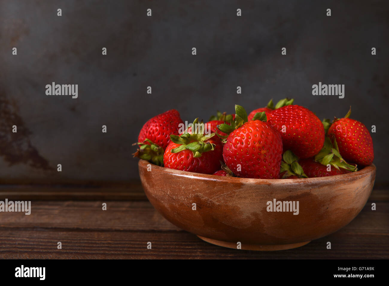 Horizontale Stillleben mit einer Schüssel voll von frisch gepflückten Erdbeeren auf einem Holztisch. Querformat mit Textfreiraum. Stockfoto