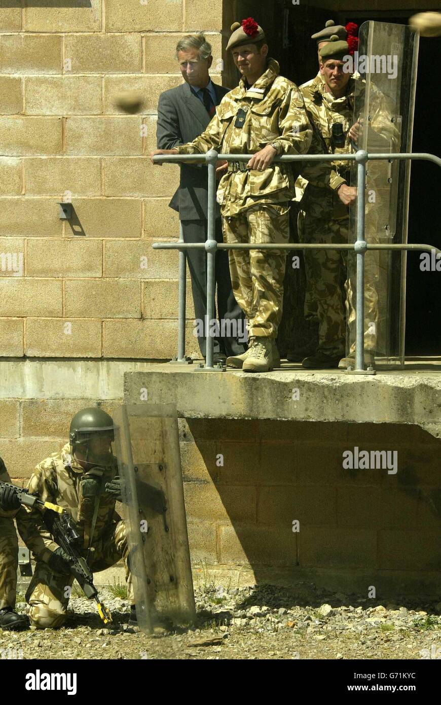 Der Prinz von Wales (oben links) sieht eine Demonstration der Massenkontrolle hinter einem Aufstandsschild bei seinem Besuch im 1. Bataillon The Black Watch (Royal Highland Regiment) in einem Trainingsdorf in der Nähe von Warminster in der Salisbury-Ebene vor ihrer Rückkehr in den Irak. Stockfoto