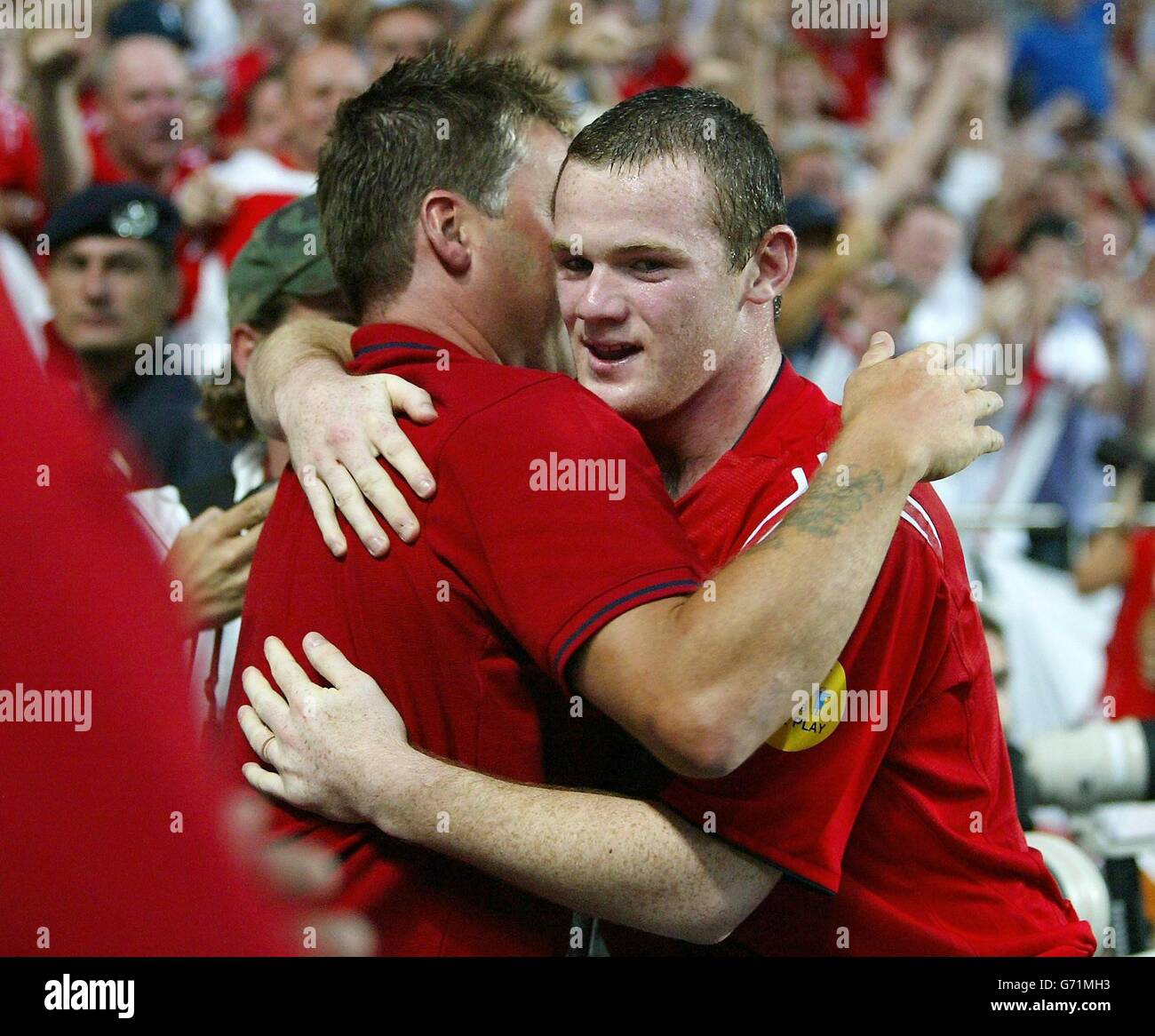 Der englische Wayne Rooney (rechts) umarmt einen Fan, als er beim Estadio de Luz in Lissabon, Portugal, feiert, dass er sein zweites Tor gegen Kroatien während der Euro 2004, ersten Runde, Gruppe B, erzielt hat. England gewann 4-2. Stockfoto