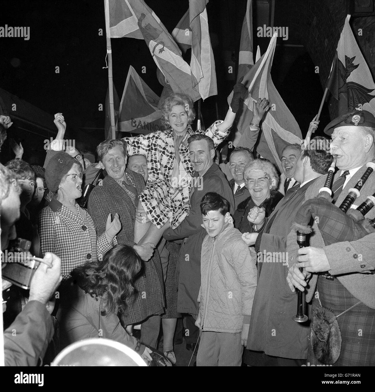 Der Klang der Dudelsäcke und ein Winken schottischer Flaggen, um die Ankunft von Winnie Ewing, der neuen schottischen Nationalabgeordneten für Hamilton, in Kings Cross Station, London, anzukündigen. Stockfoto