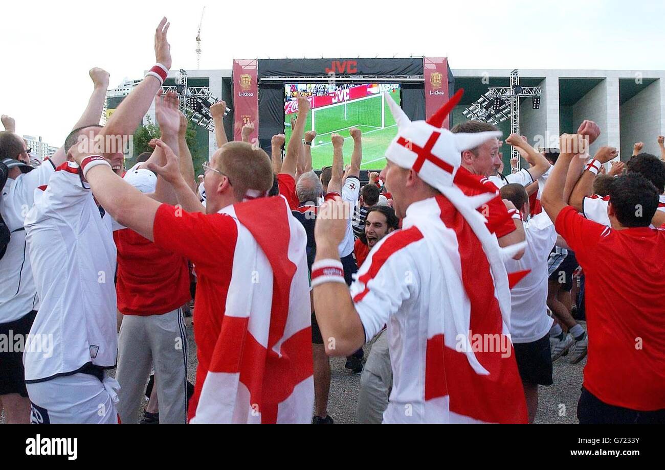 England-Fans feiern Wayne Rooneys Tor, während sie das EM 2004-Spiel zwischen England und Kroatien auf der Großleinwand im Fan Park, Praca das Nacoes, Lissabon, Portugal, sehen. Stockfoto