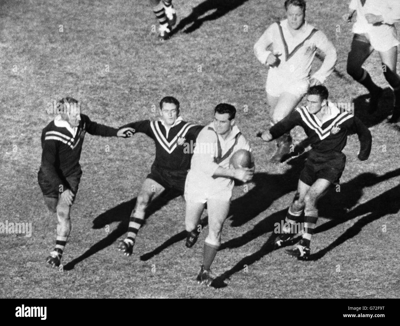 Derek Turner (Wakefield Trinity) versucht, drei australischen Spielern auszuweichen, als er im ersten Testspiel gegen Australien auf dem Sydney Cricket Ground einen seiner vielen guten Runs für Großbritannien macht. Die australischen Spieler (von l-r) Johnny Raper (New South Wales), Barry Muir (Queensland) und Reg Gasnier (New South Wales). Großbritannien gewann das Spiel mit 31:12. Stockfoto