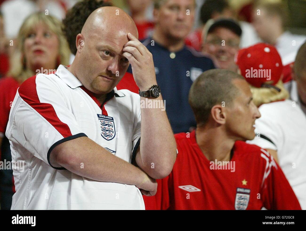 England-Fans zeigen ihre Niedergeschlagenheit nach dem plötzlichen Todesurteil im Viertelfinale der Euro 2004 gegen Portugal im Estadio da Luz in Lissabon, Portugal. England verlor gegen Portugal 6-5 auf Strafen, nachdem das Spiel in einem Unentschieden von 2-2 nach Verlängerung endete. Stockfoto