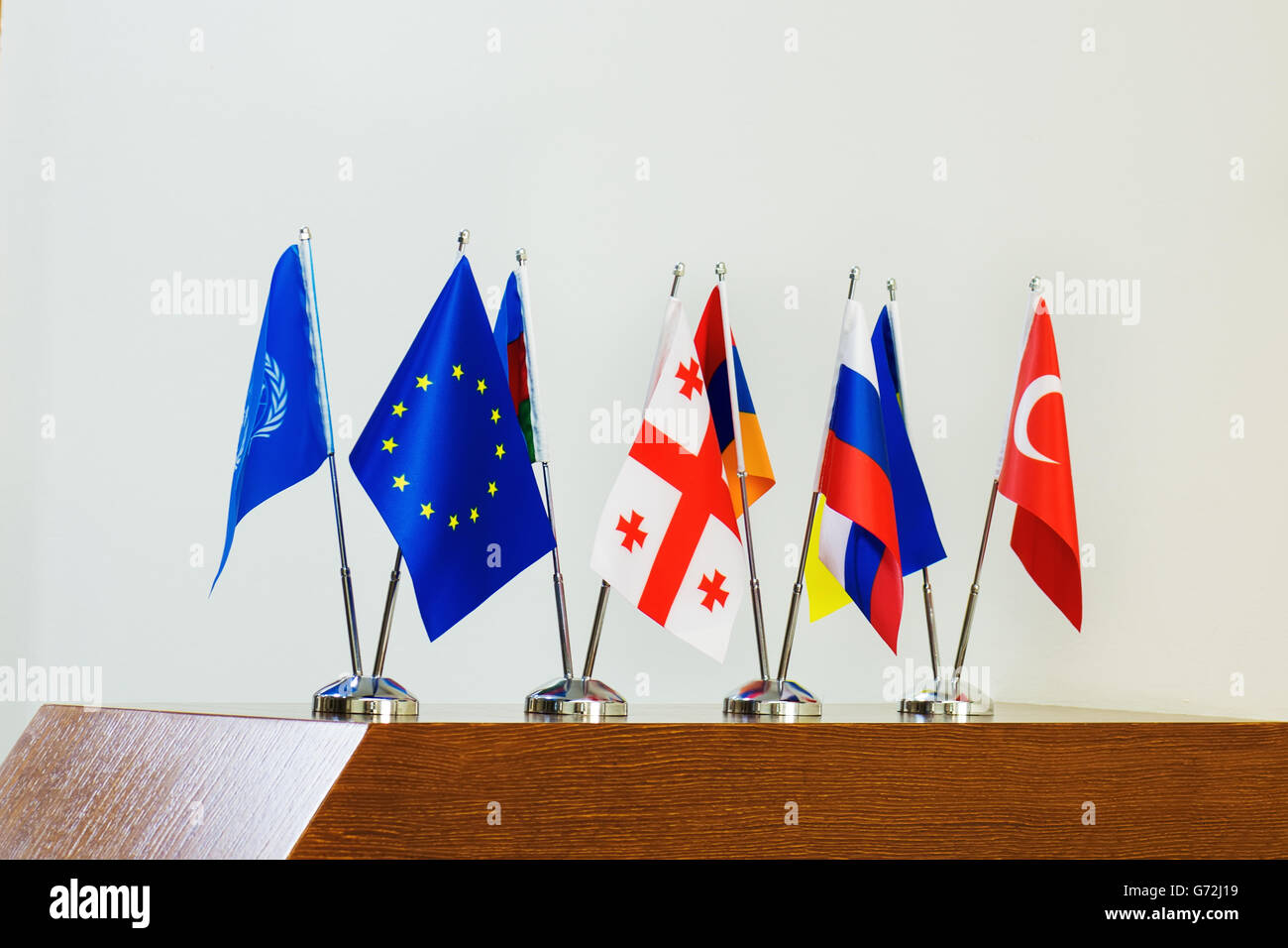 Miniatur-Flaggen der europäischen Länder und die EU-Flagge auf Fahnenmasten auf einem Holztisch. Stockfoto