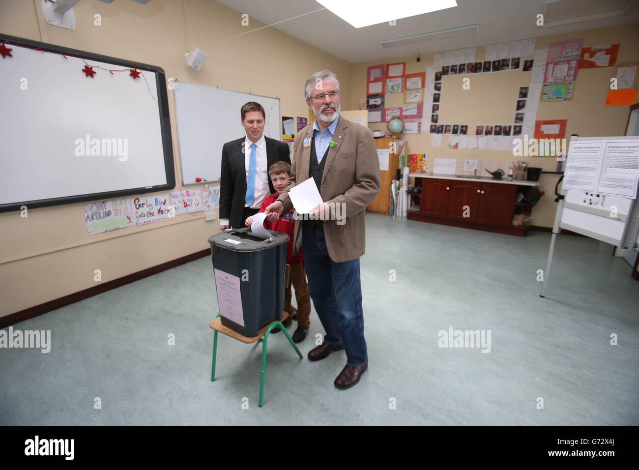 Sinn Fein-Chef Gerry Adams TD, begleitet von dem MdEP-Kandidaten Matt Carthy, und Matts-Sohn Sean, acht Jahre alt, als er bei den lokalen und Europawahlen in der Doolargy National School, Ravensdale, Co. Louth, Irland, seine Stimme abgibt. Stockfoto