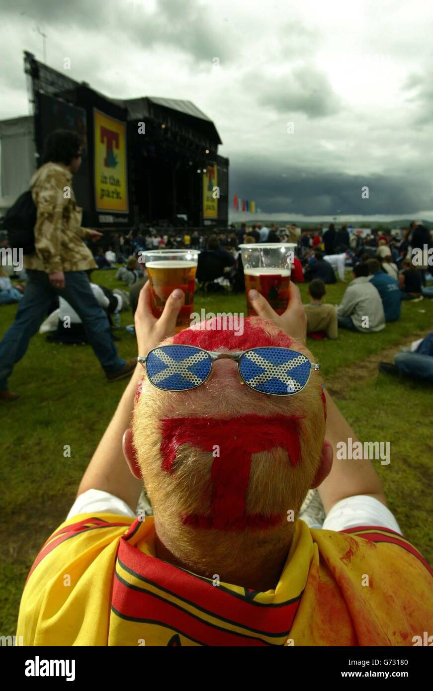 Ein Nachtschwärmer, der mit dem T-in the Park Logo auf die Hauptbühne während des zweitägigen Musikfestivals in Balado bei Stirling blickt. Stockfoto
