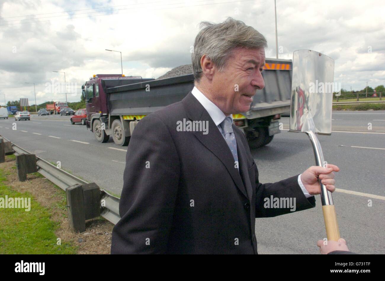 Der Verkehrsminister Seamus Brennan hat heute, am 12. Juli 2004, bei einer feierlichen Zeremonie, bei der er den ersten Spatenstich für den Baubeginn der 230 Millionen Euro teuren Naas Road-Erweiterung in Kill, Co. Kildare, Irland. Die bestehende zweispurige Fahrbahn N7 wird auf 3 Fahrspuren zwischen Rathcoole und dem Naas-By-Pass erweitert, die Fertigstellung wird voraussichtlich im Frühjahr 2006 erfolgen. Das Projekt besteht aus zwei Abschnitten, wobei der Kildare-Abschnitt 8.75 km lang ist und der South Dublin-Abschnitt 5,5 km lang ist. Stockfoto