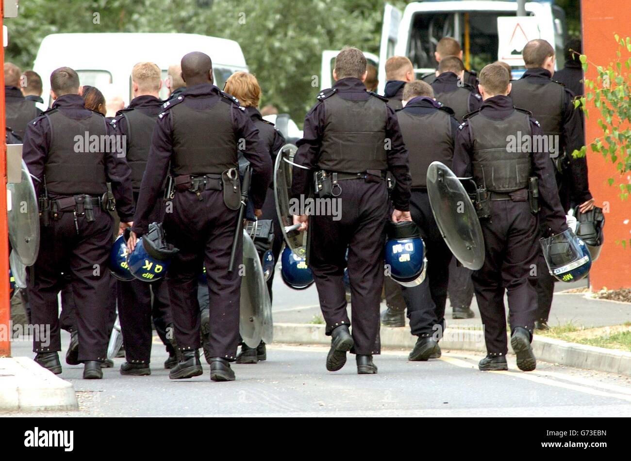 Die Polizei wartet am Dienstag, dem 20. Juli 2004, vor dem Harmondsworth Immigration Inhaftierung Center in der Nähe des Londoner Flughafens Heathrow, wo eine „seriöse“ Störung ausbrach, nachdem gestern die Leiche eines Asylbewerbers entdeckt worden war, und die Mitarbeiter mussten sich aus Sicherheitsgründen zurückziehen. Die Polizei untersucht den Tod, aber es wird angenommen, dass er nicht verdächtig ist. Stockfoto