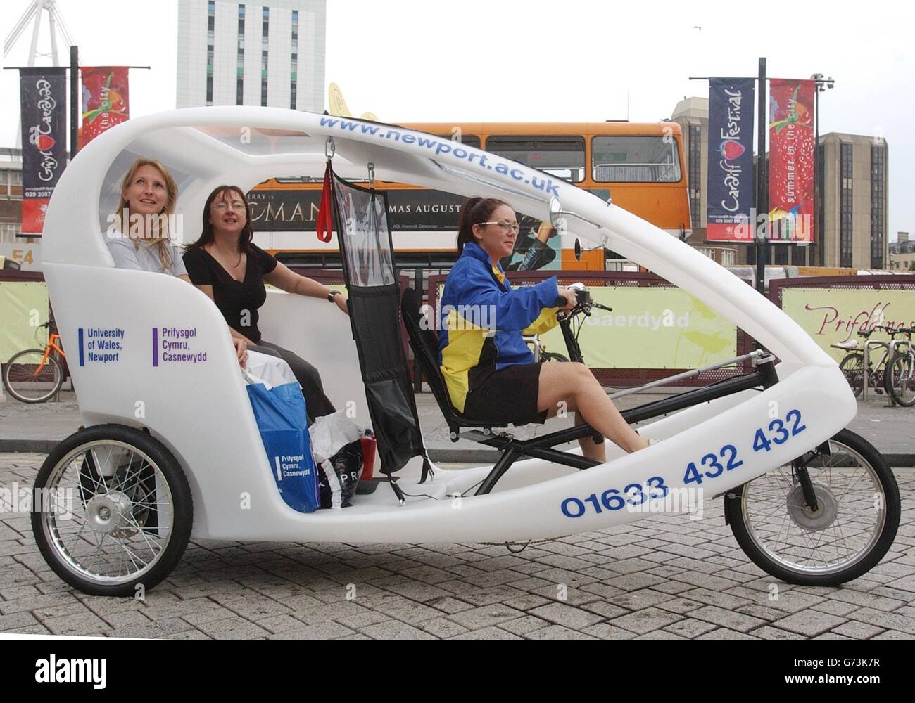 Victoria Jones liefert die Energie für das Pedal-angetriebene Taxi und die Passagiere Helen Beddow (nächste Kamera) und Jackie Harris in Cardiff reisen in einem Stil in den neuen Cruiser. Cardiff ist der erste Platz in Großbritannien außerhalb Londons, der Gastgeber von pedalbetriebenen City Cruisern ist. Stockfoto